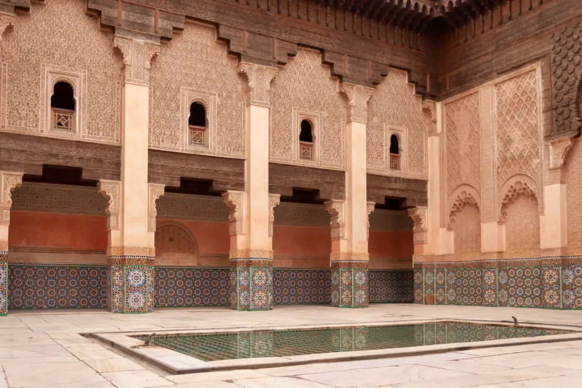 The courtyard of the Ben Youssef Madrasa, with carved stucco, cedar wood, zellige tiles and a long pool